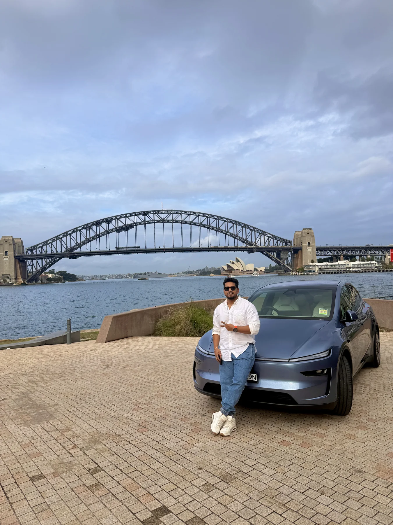 The ABMods founder leaning on a Model Y in front of the Sydney Harbour Bridge